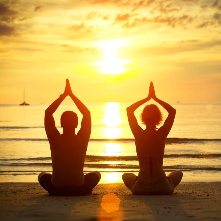 Image of two people meditating at the beach