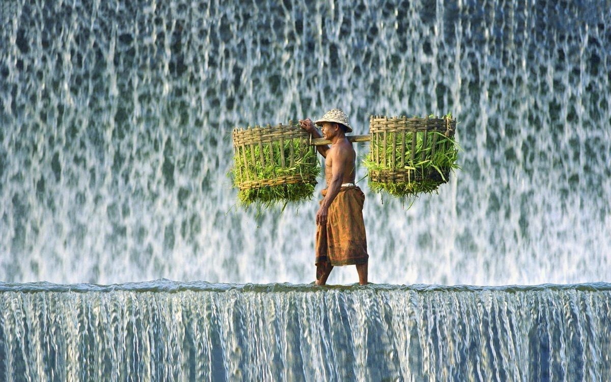 Image of a man walking with baskets over waterfall