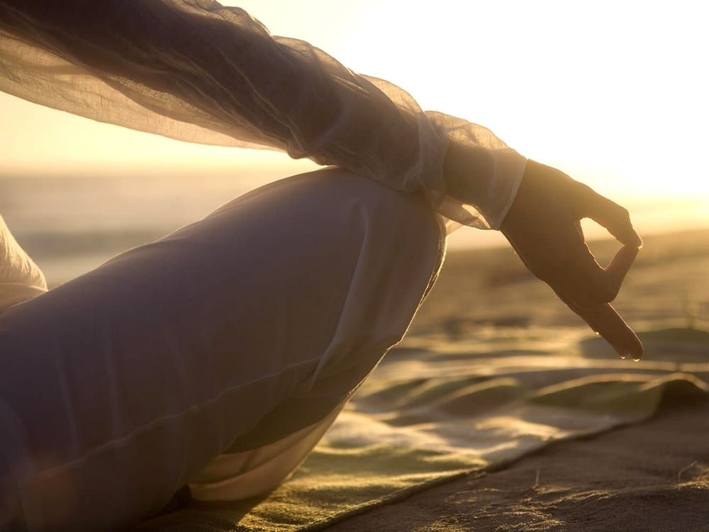 Image of a woman meditating at the beach